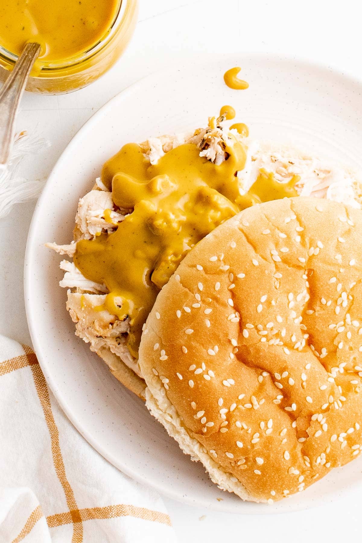 Sandwich bun with pulled chicken and mustard bbq sauce.