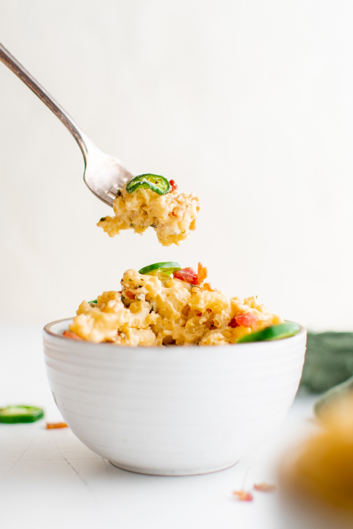 Small white bowl with baked mac and cheese and a fork lifting a bite. 