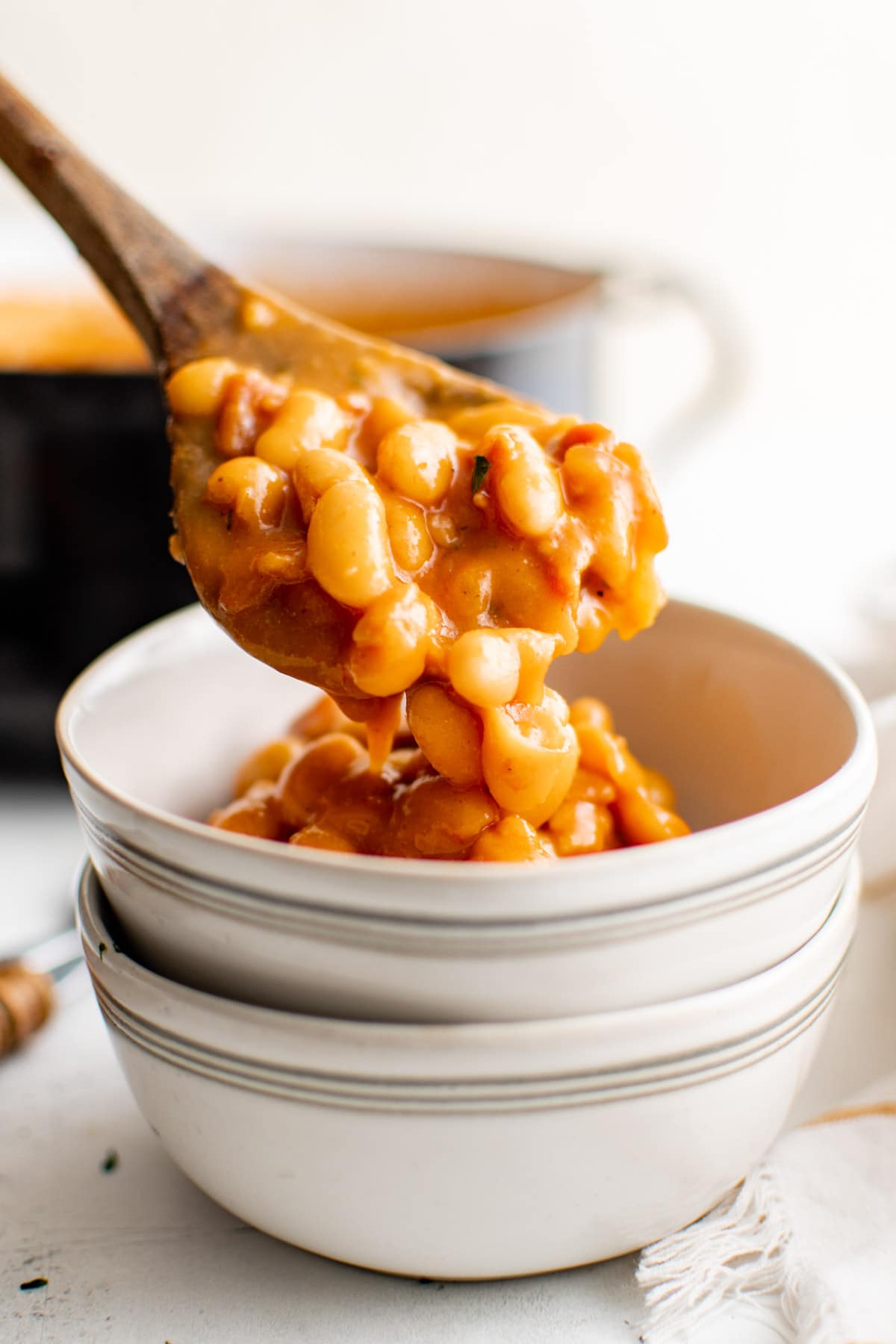 Wooden spoon and a small bowl with pork and beans. 