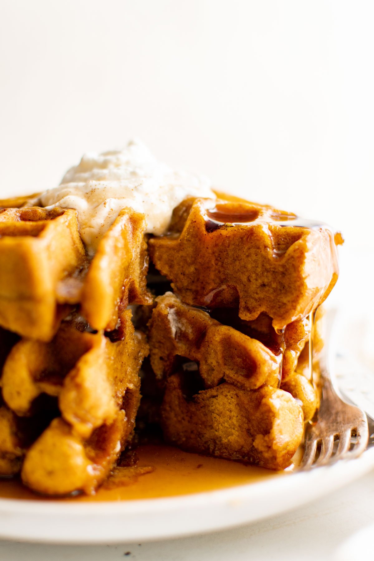 Stack of waffles with whipped cream on top.