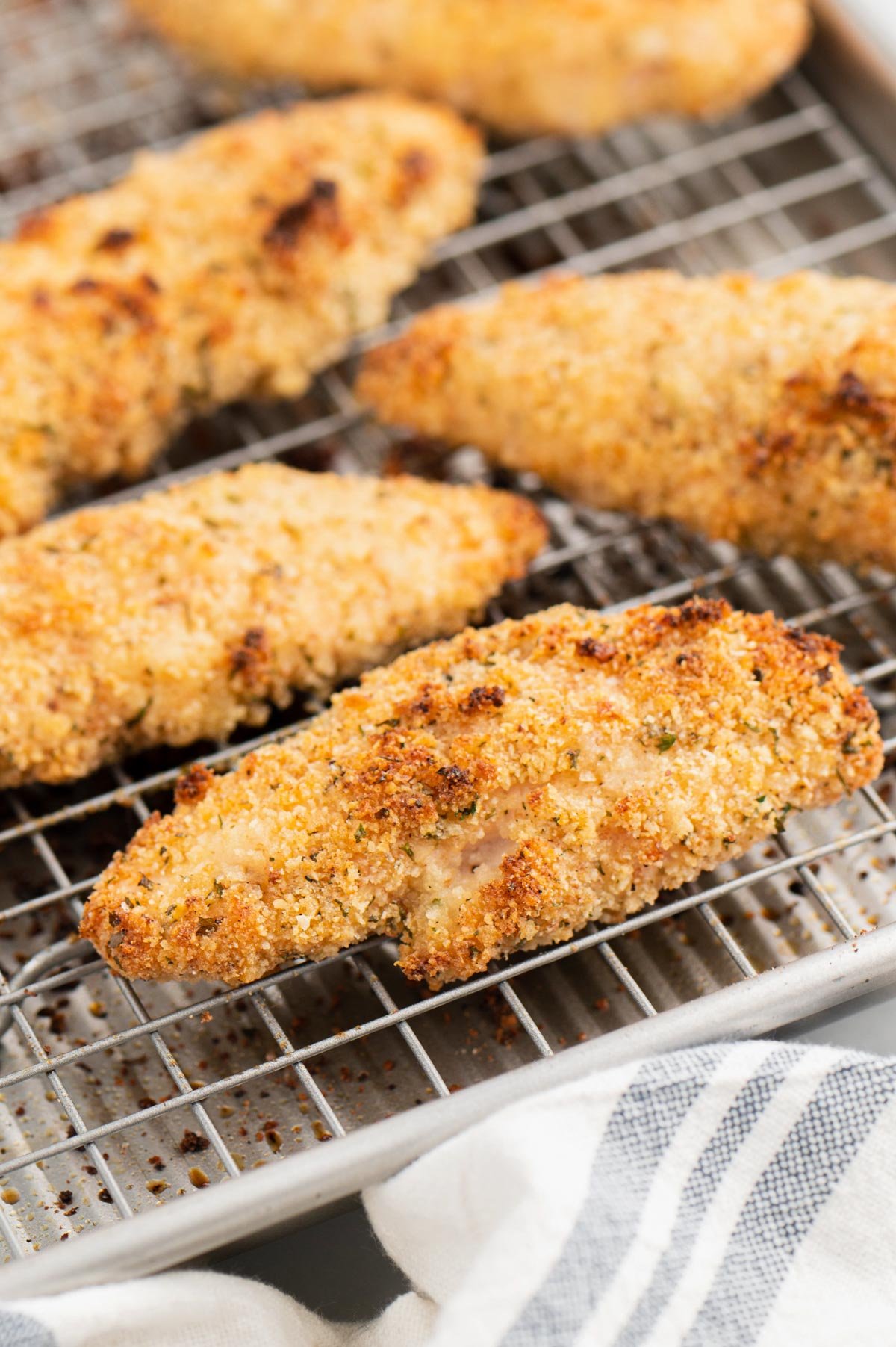 Close up of baked chicken tenders on a wire rack.