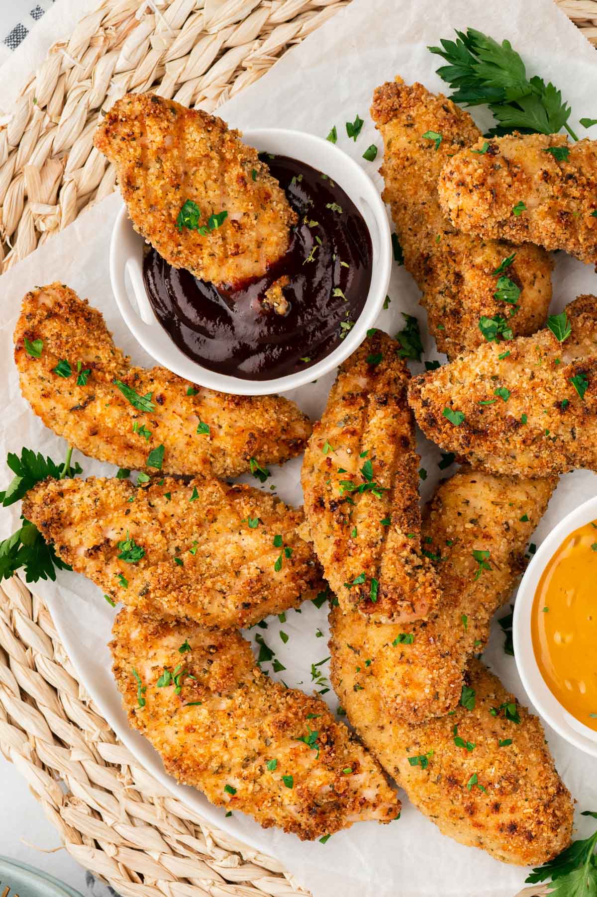 Baked chicken tenders on a white plate, a small dish of BBQ sauce.