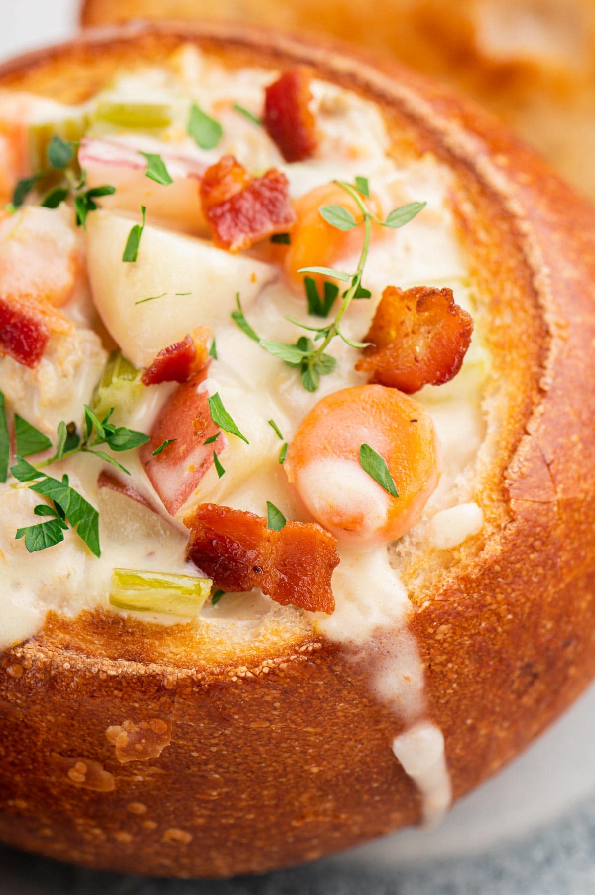 Crunchy bread bowl filled with clam chowder adn topped with bacon and parsley.
