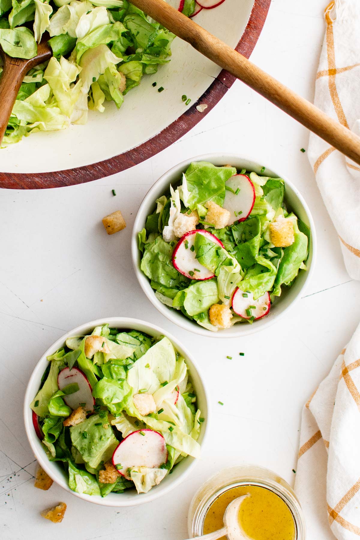 Salad bowls with salad in them, forks, serving bowl and spoon.