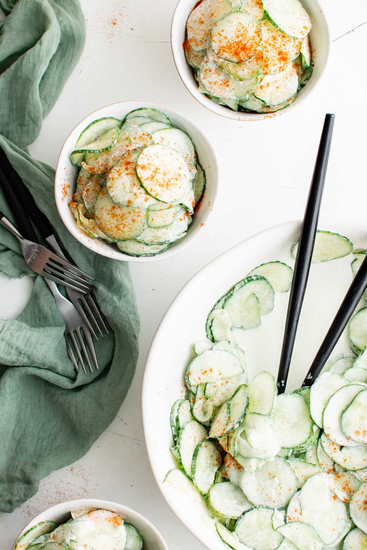 Creamy cucumber salad in small bowls and a large bowl.