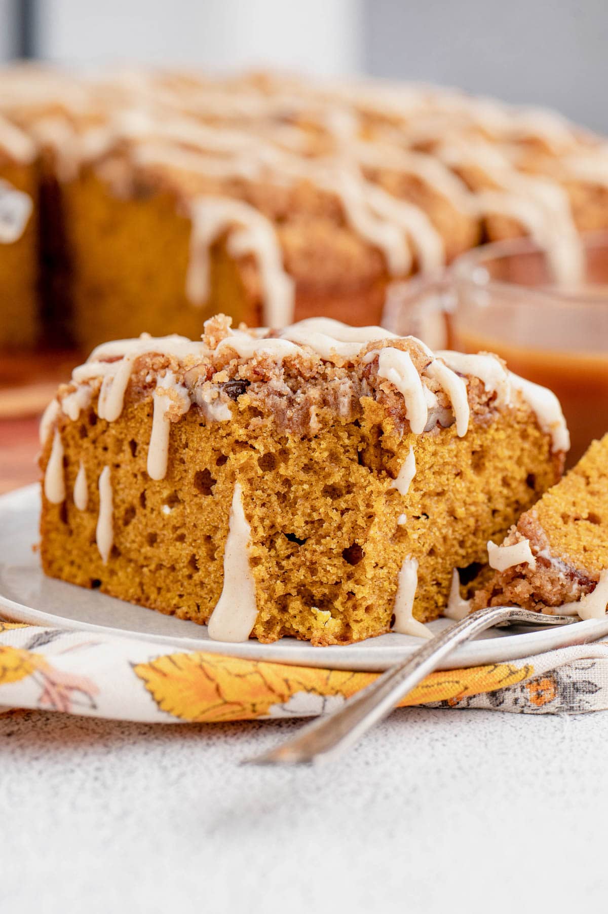 Slice of pumpkin cake on a small white plate with a fork.