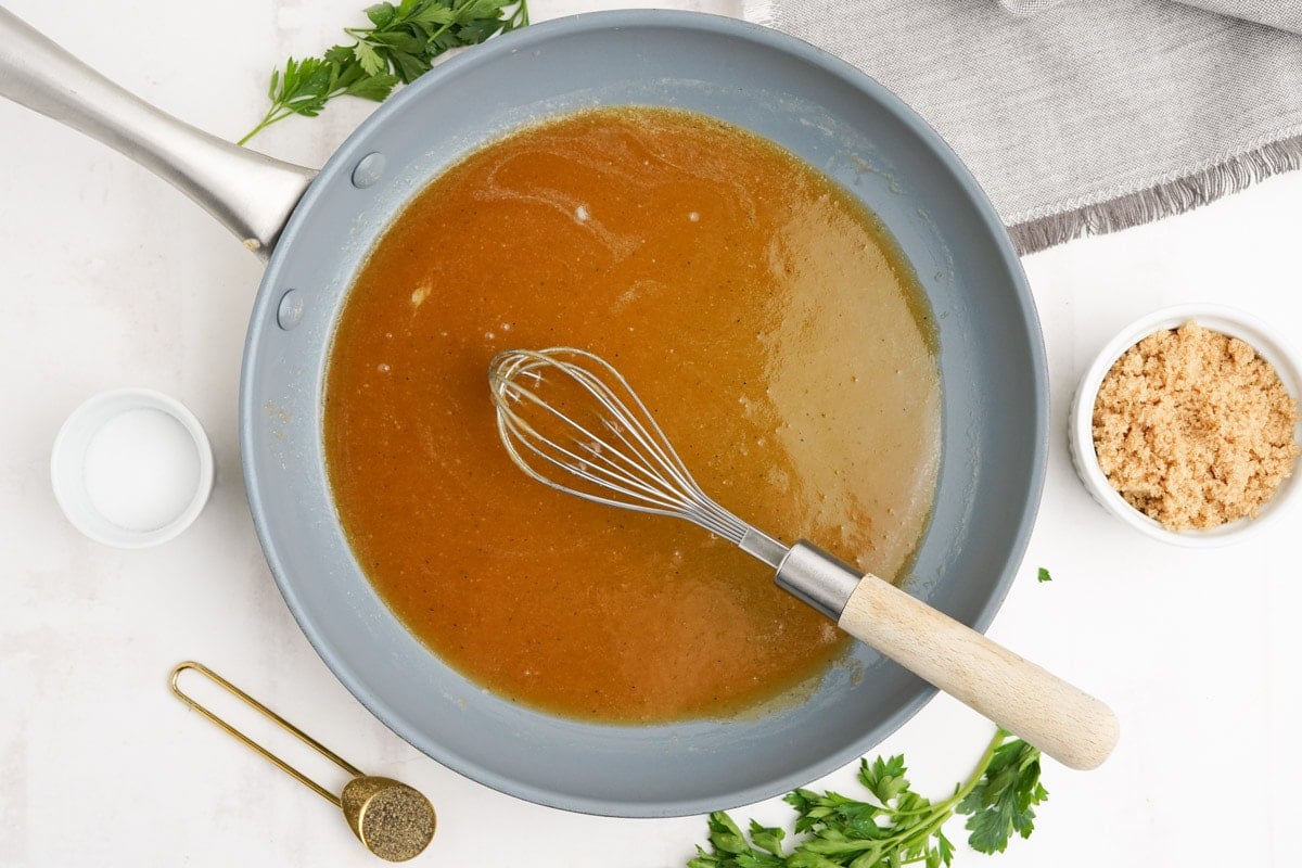 Melted brown sugar sauce in a skillet with a wire whisk.