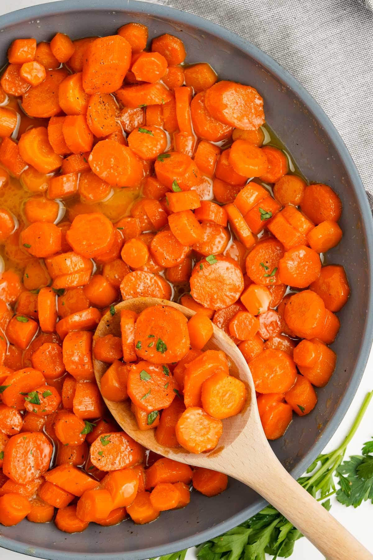 Sliced carrots glazed in a brown sugar butter sauce in a skillet.