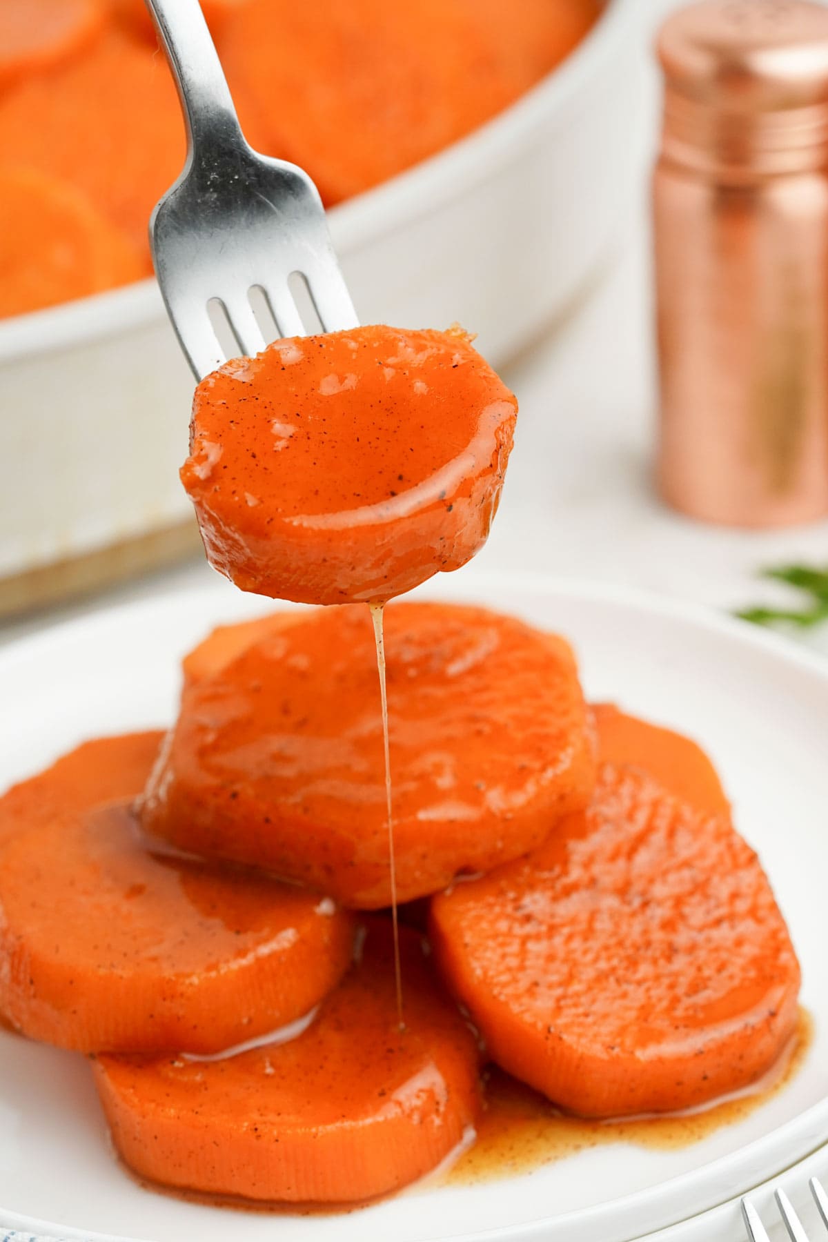 A fork holding a sliced yam over a plate.