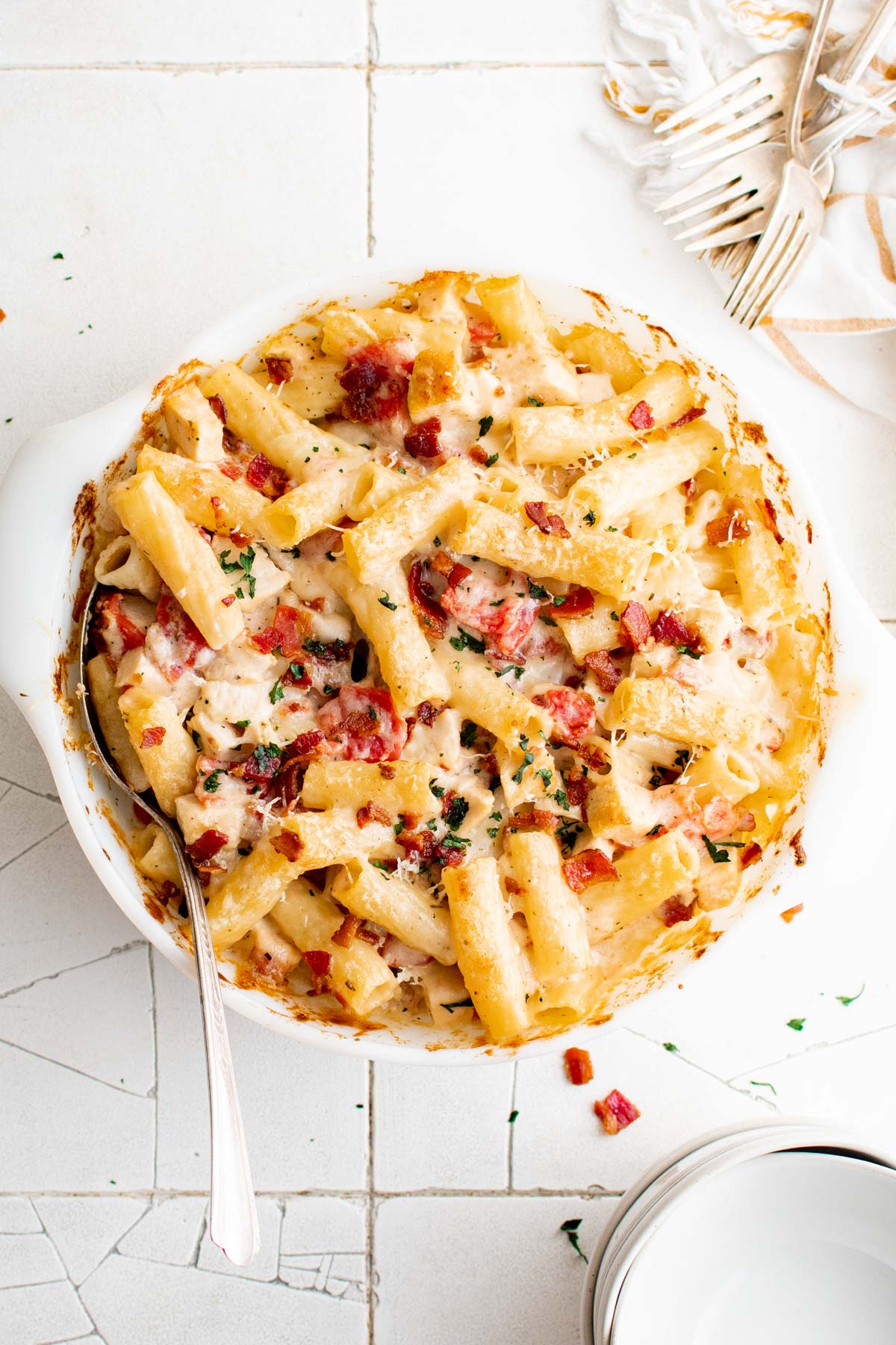 White round baking dish with baked pasta topped with bacon and cheese.