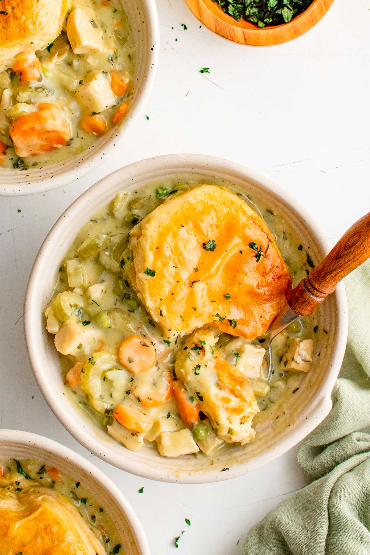 Chicken pot pie in a bowl, topped with biscuits, and a spoon.