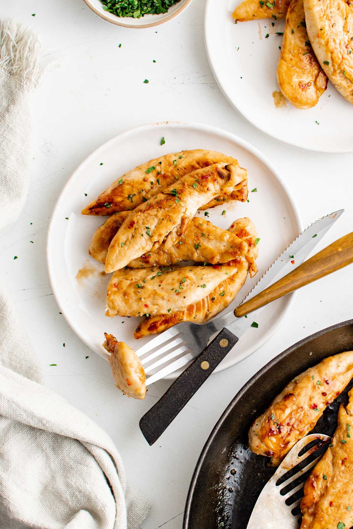 Chicken tenders on a white plate with a fork and knife.