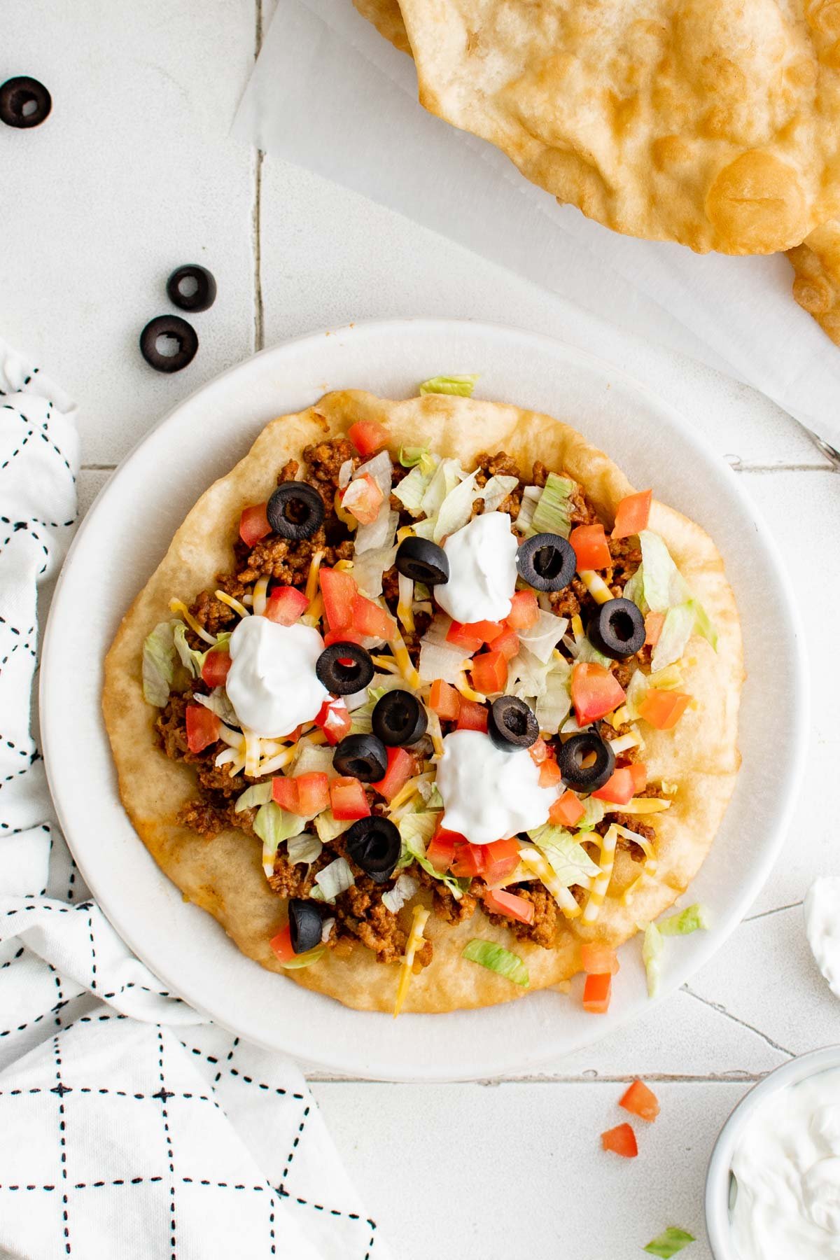 Fry bread taco with meat, cheese, sour cream and tomatoes.