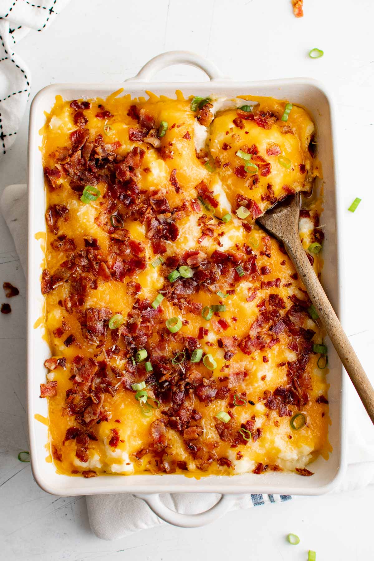 Casserole dish with mashed potatoes loaded with bacon and cheese.