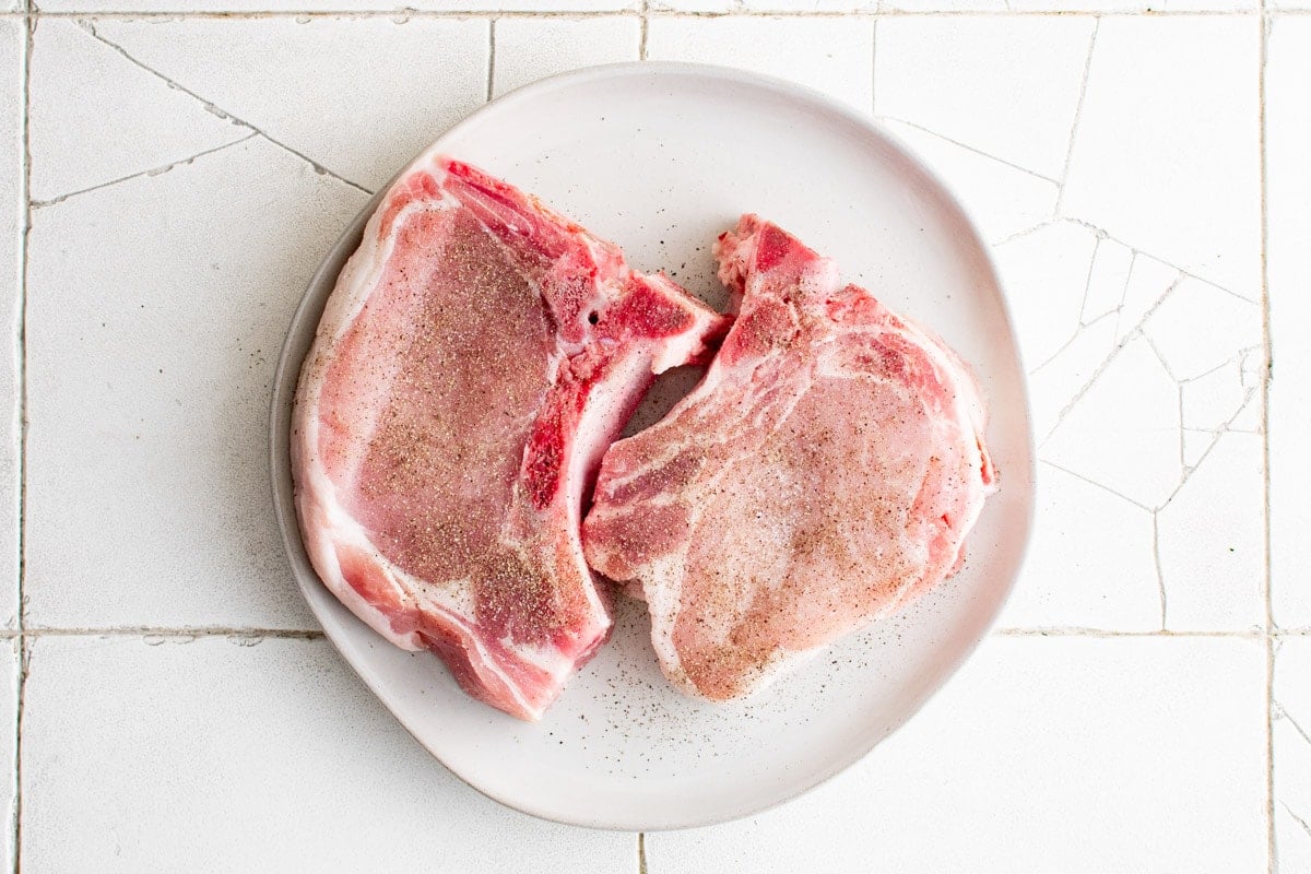 Two bone-in pork chops on a white plate