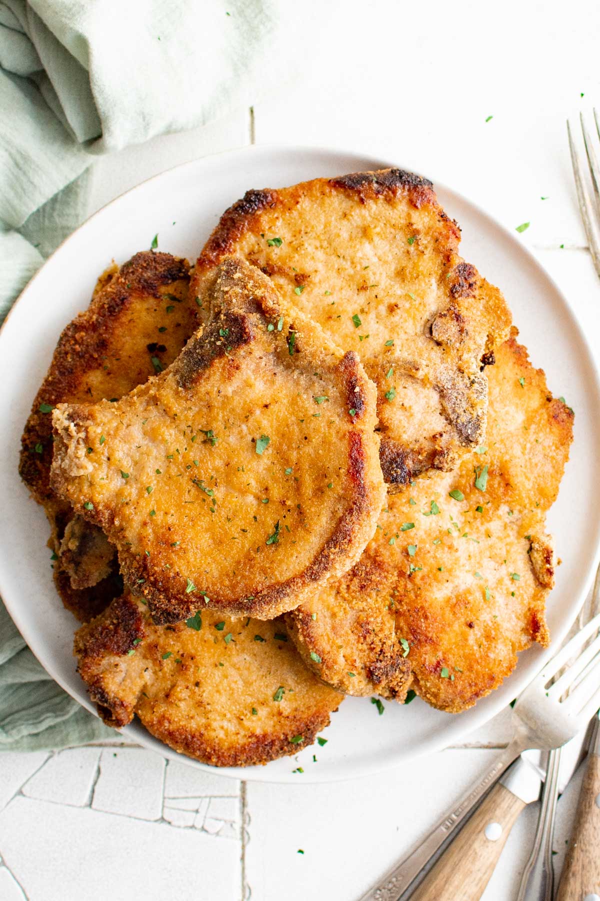 Pork chops stacked on a plate.