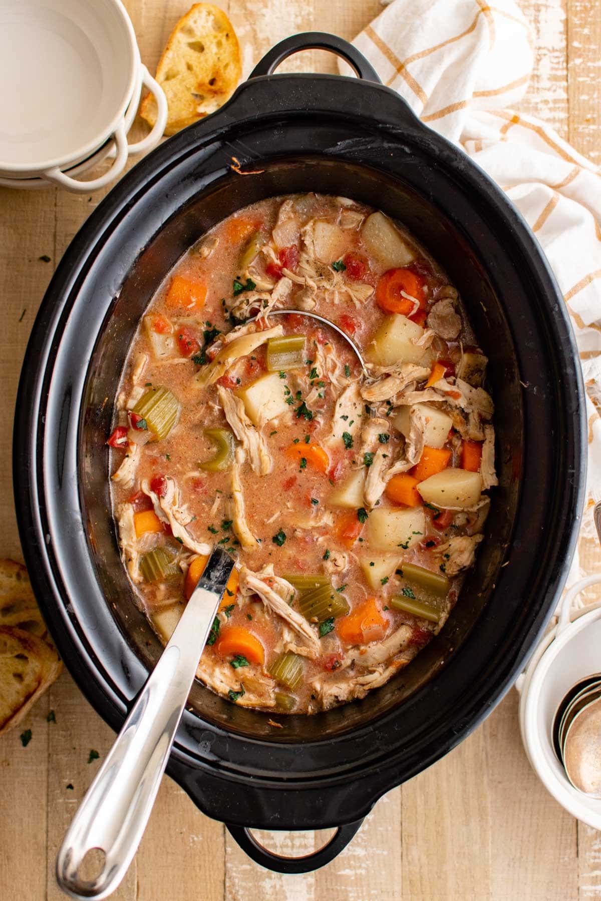 Slow cooker chicken stew in a pot with a ladle.