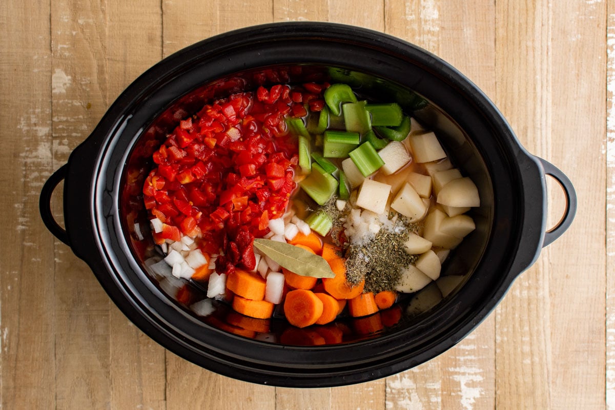 Crock pot with vegetables like carrots, celery and potatoes.