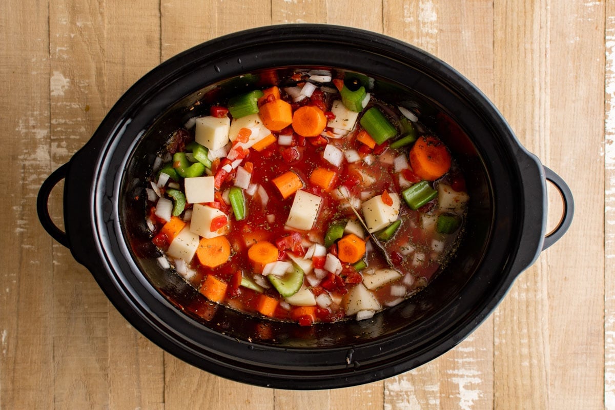 Slow cooker pot with vegetable, potatoes and broth.
