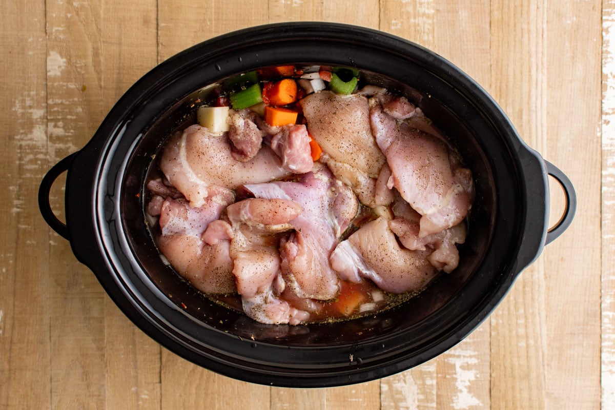 Slow cooker with veggies and chicken thighs.