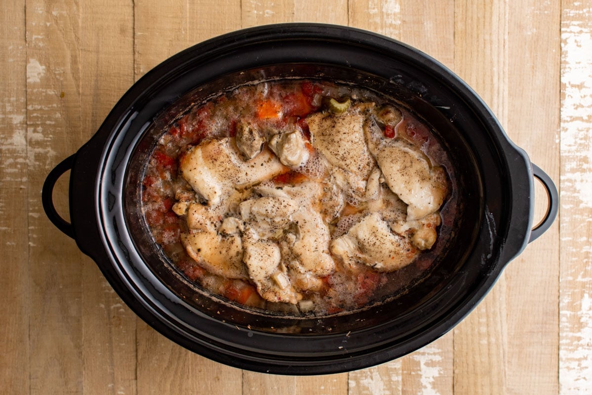 Slow cooker chicken stew with cooked chicken thigh.