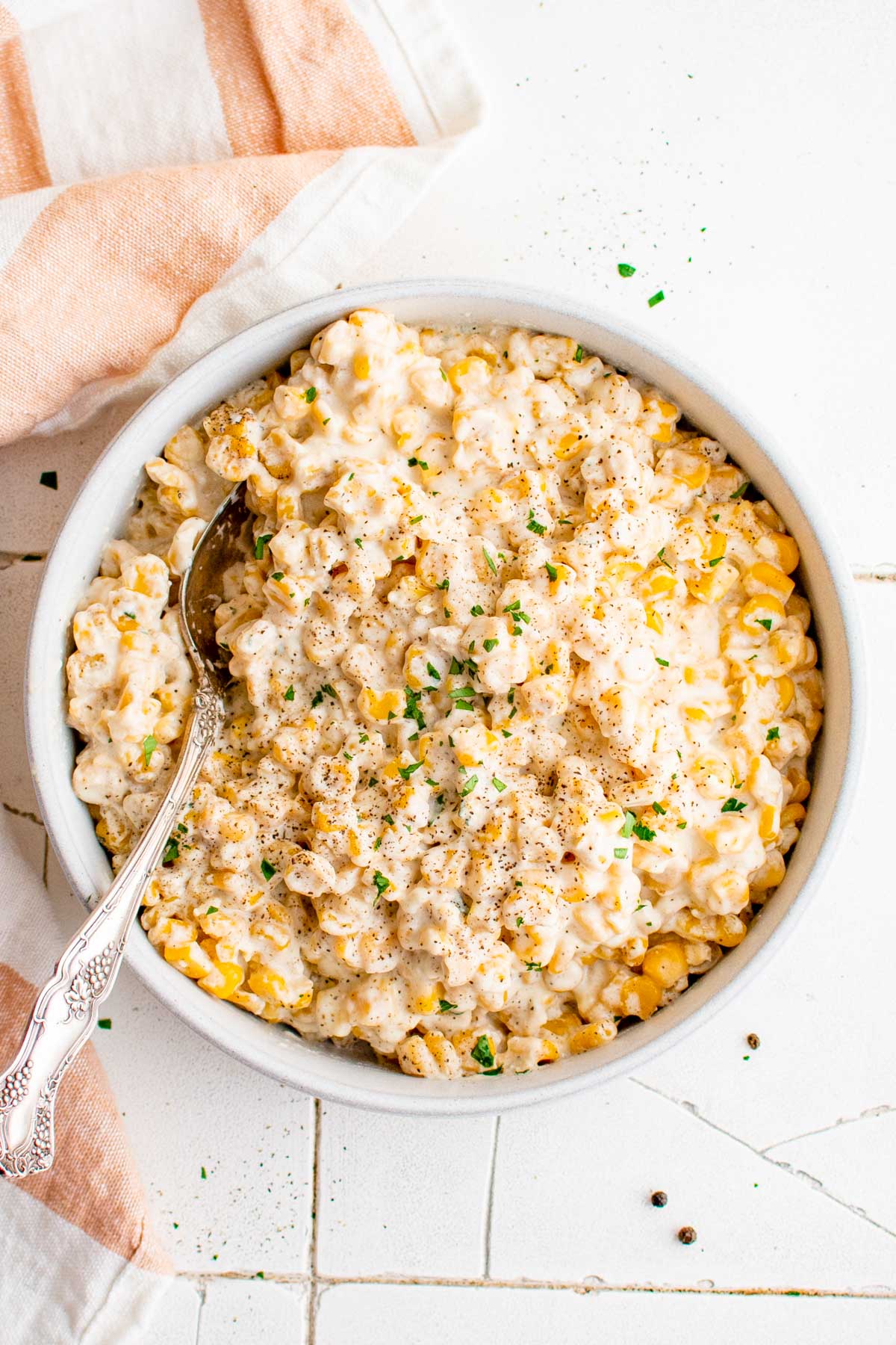 A large bowl of cream style corn with a serving spoon.