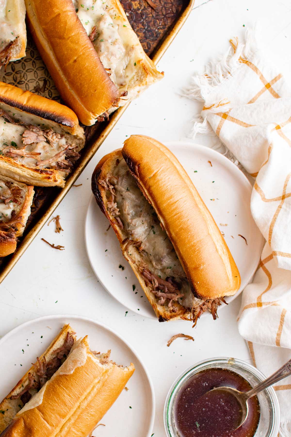 Slow Cooker shredded beef sandwiches with cheese on white plates. 