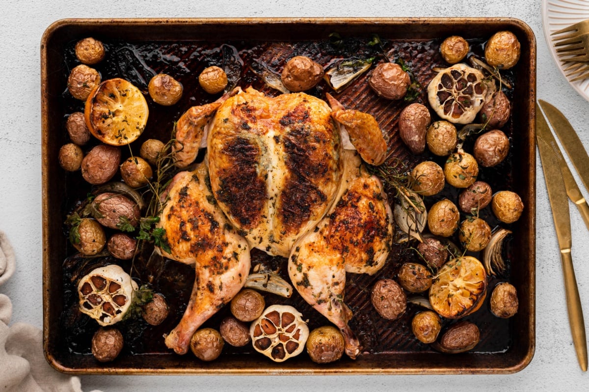 Spatchcock chicken, potatoes, lemons and garlic on a sheet pan.