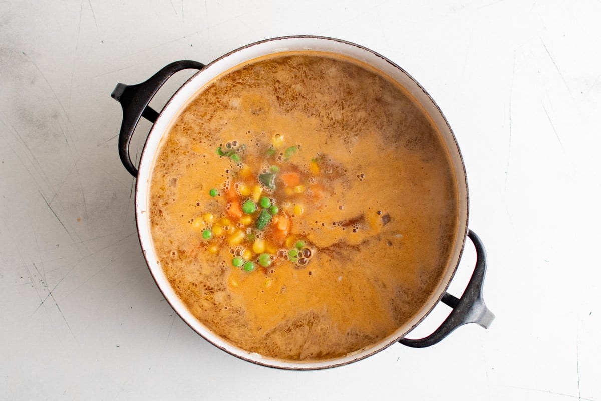 Simmering soup with red broth and vegetables.