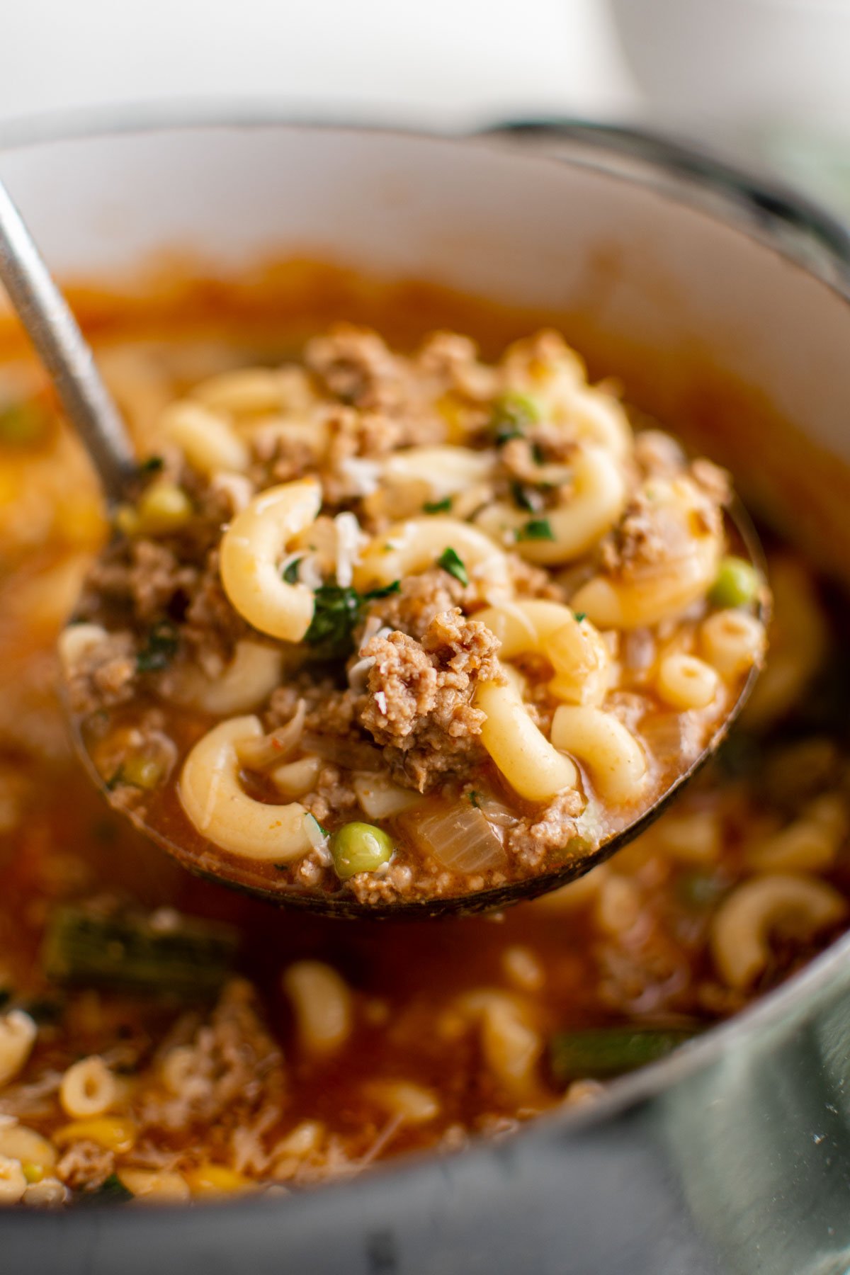 A ladle holding a serving of hamburger soup.