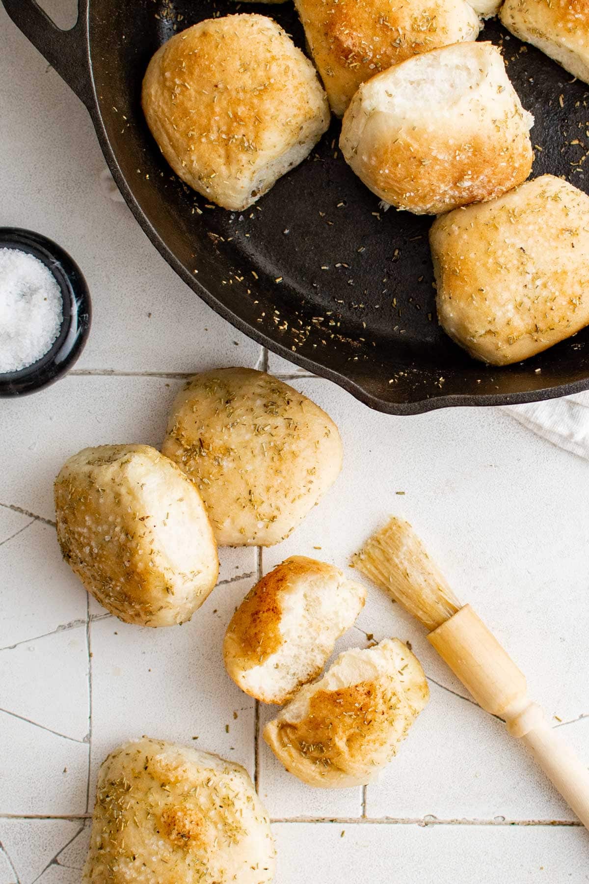 Overhead shot of skillet with rolls in it, and a few sitting next to the skillet. 