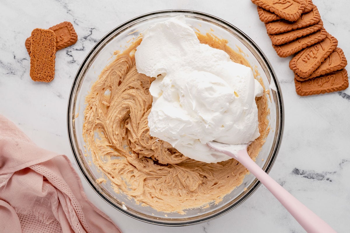 Whipped cheesecake batter ih a glass bowl with whipped topping.