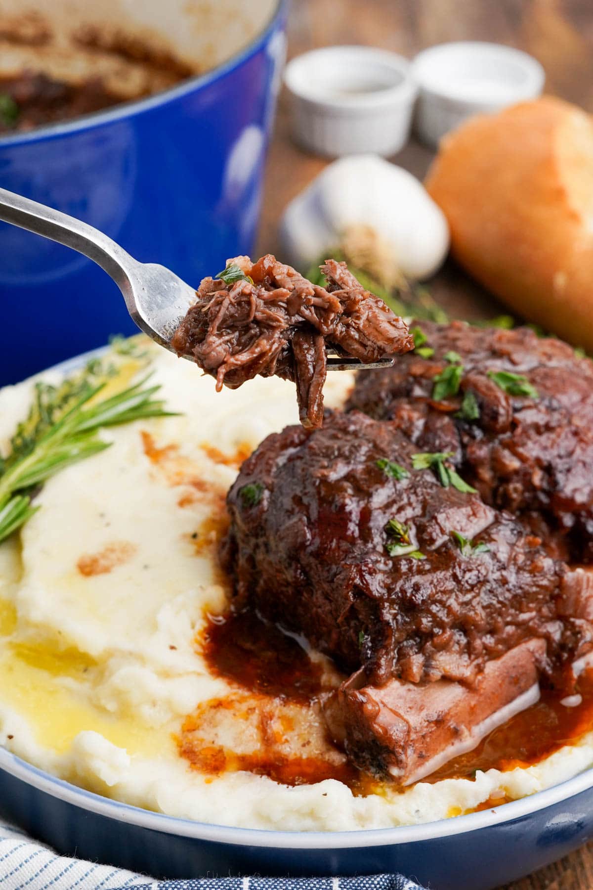 Plate of mashed potatoes and short ribs, fork raising a piece of beef.