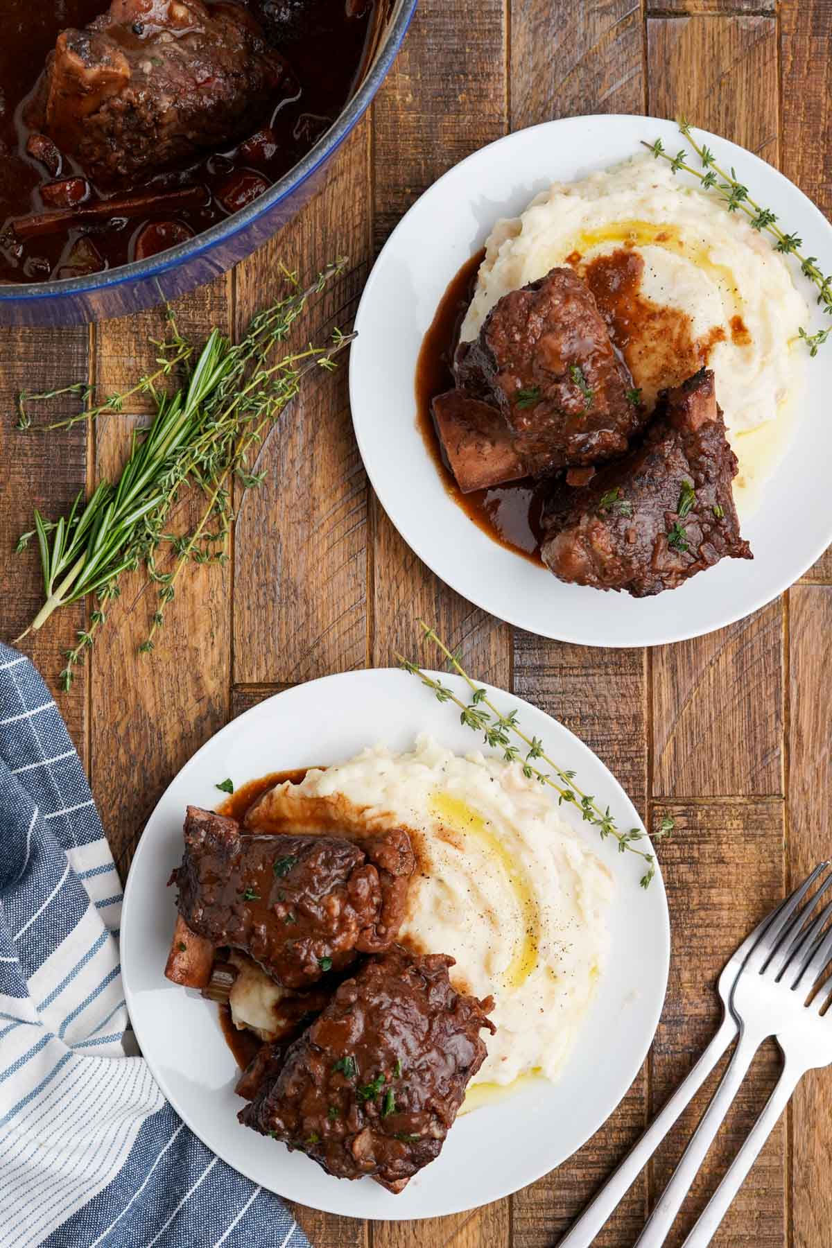 Two plates of braised short ribs and mashed potatoes.