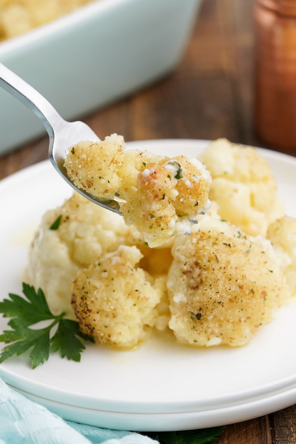 Cauliflower gratin serving on a white plate with a fork.