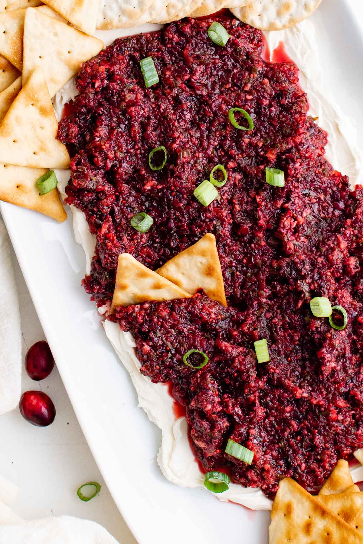 Cranberry Jalapeno Dip on top of cream cheese, with crackers dipped in it..