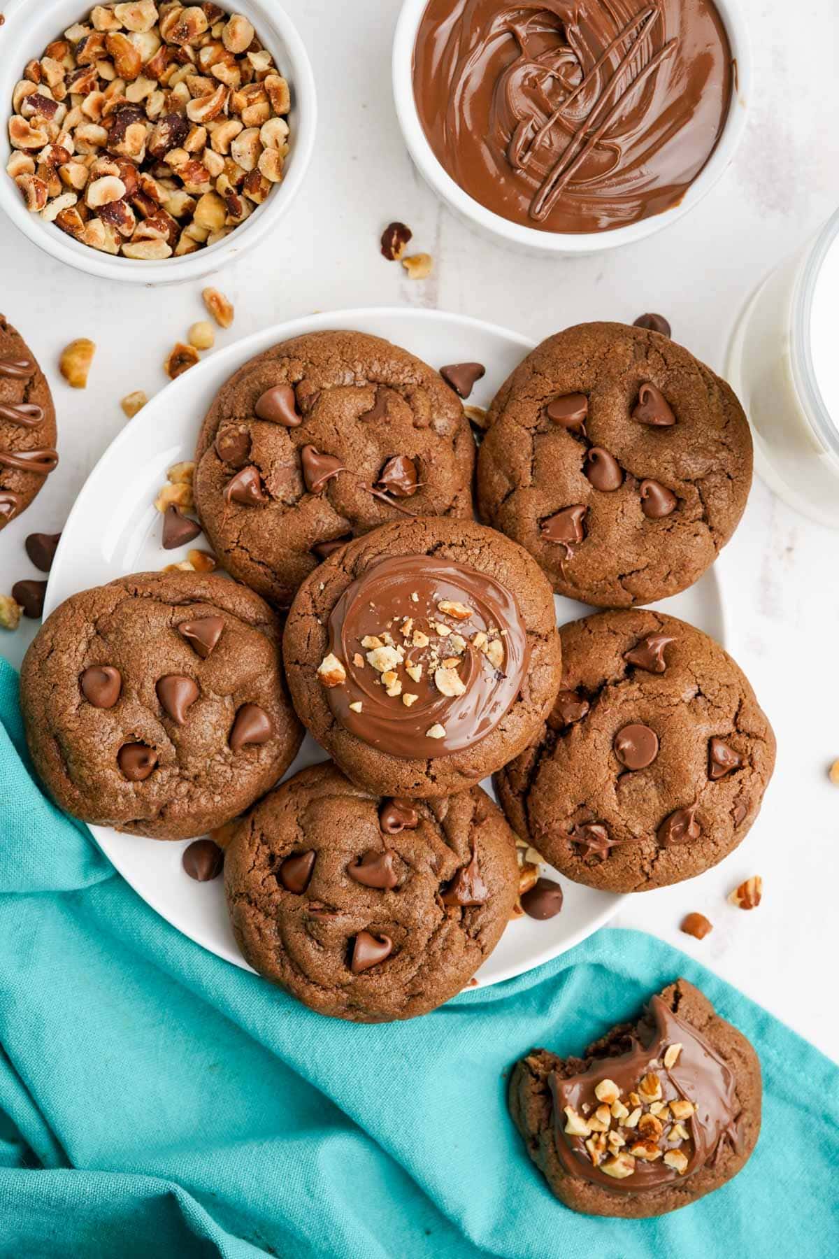 Nutella Cookies with frosting, hazelnuts and chocolate chips, on a plate, with an aqua mapkin.