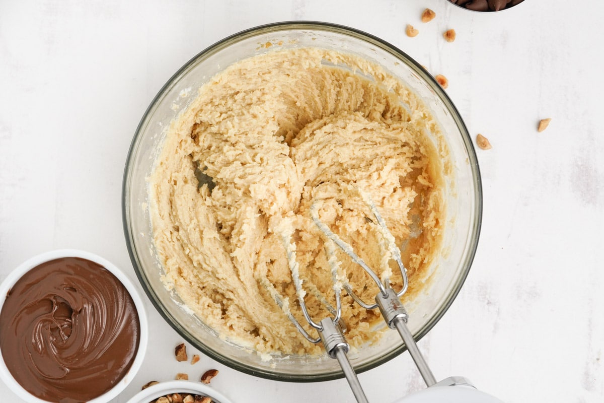 Cookie dough in a bowl with beaters from a hand mixer.