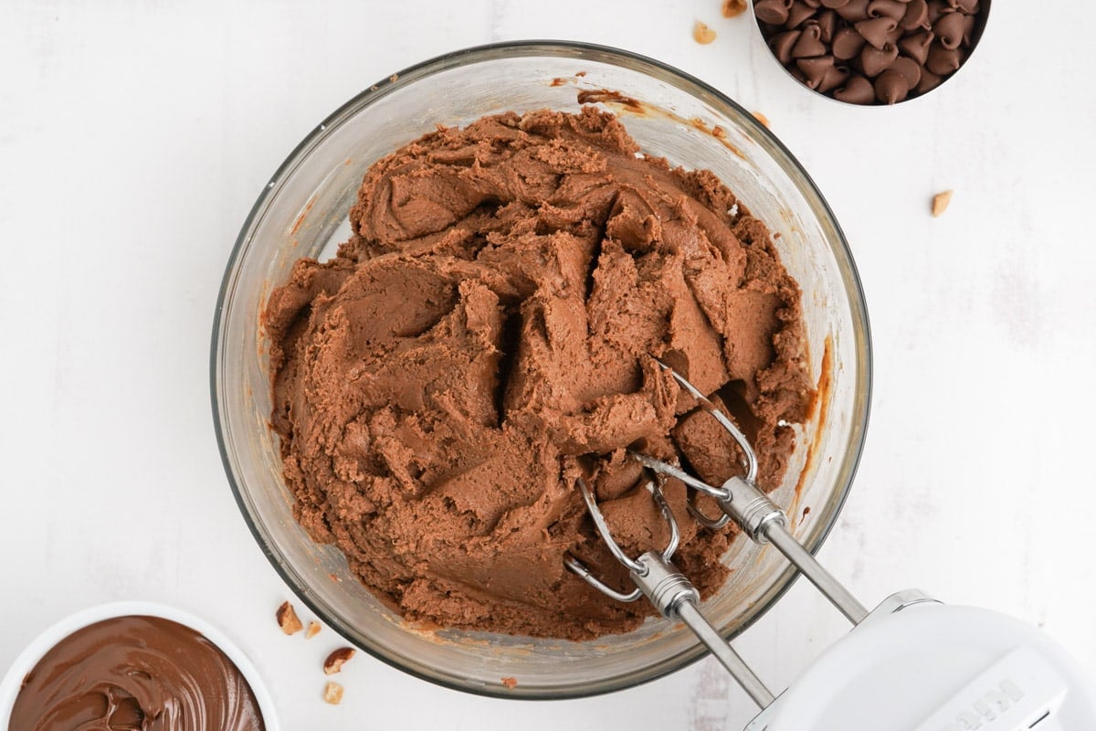 Chocolate cookie dough in a bowl with beaters from a hand mixer. 