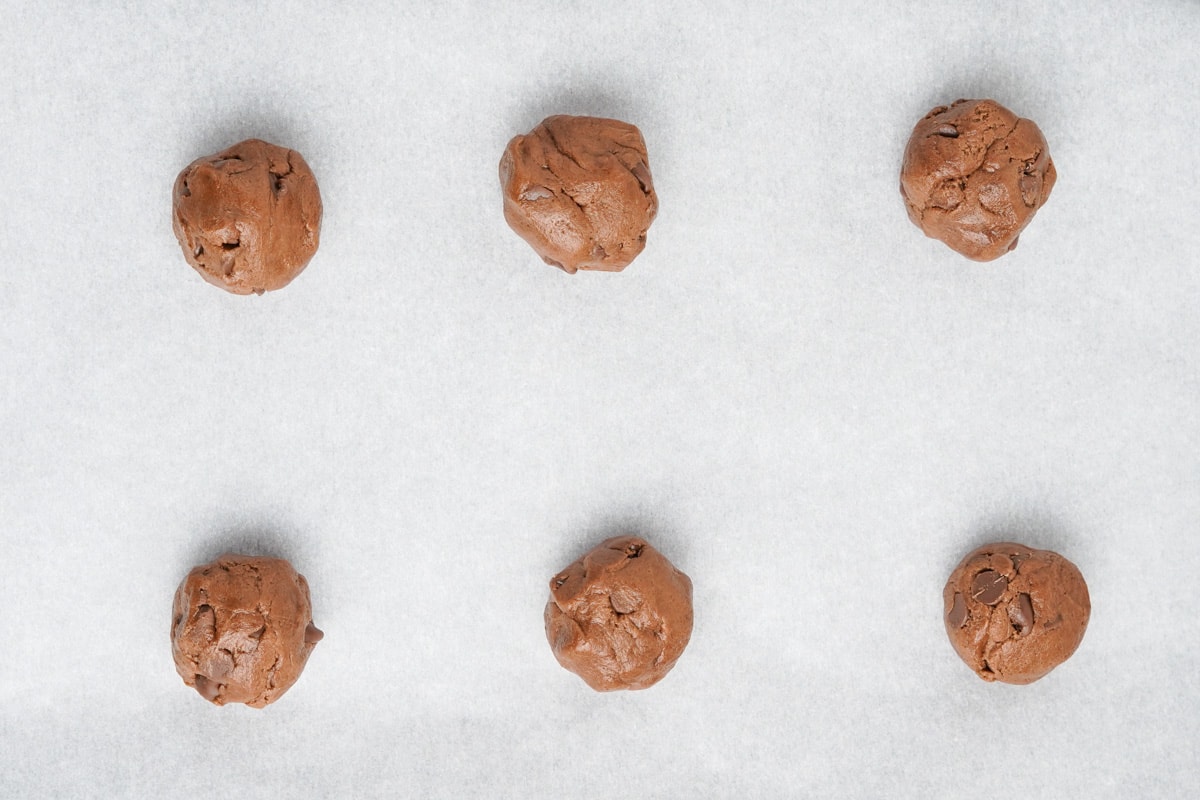Balls of chocolate cookie dough on a baking sheet. 
