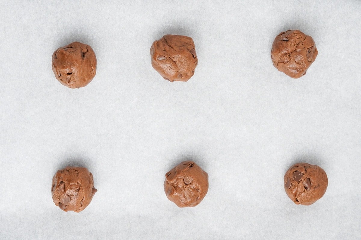 Balls of chocolate cookie dough on a baking sheet. 