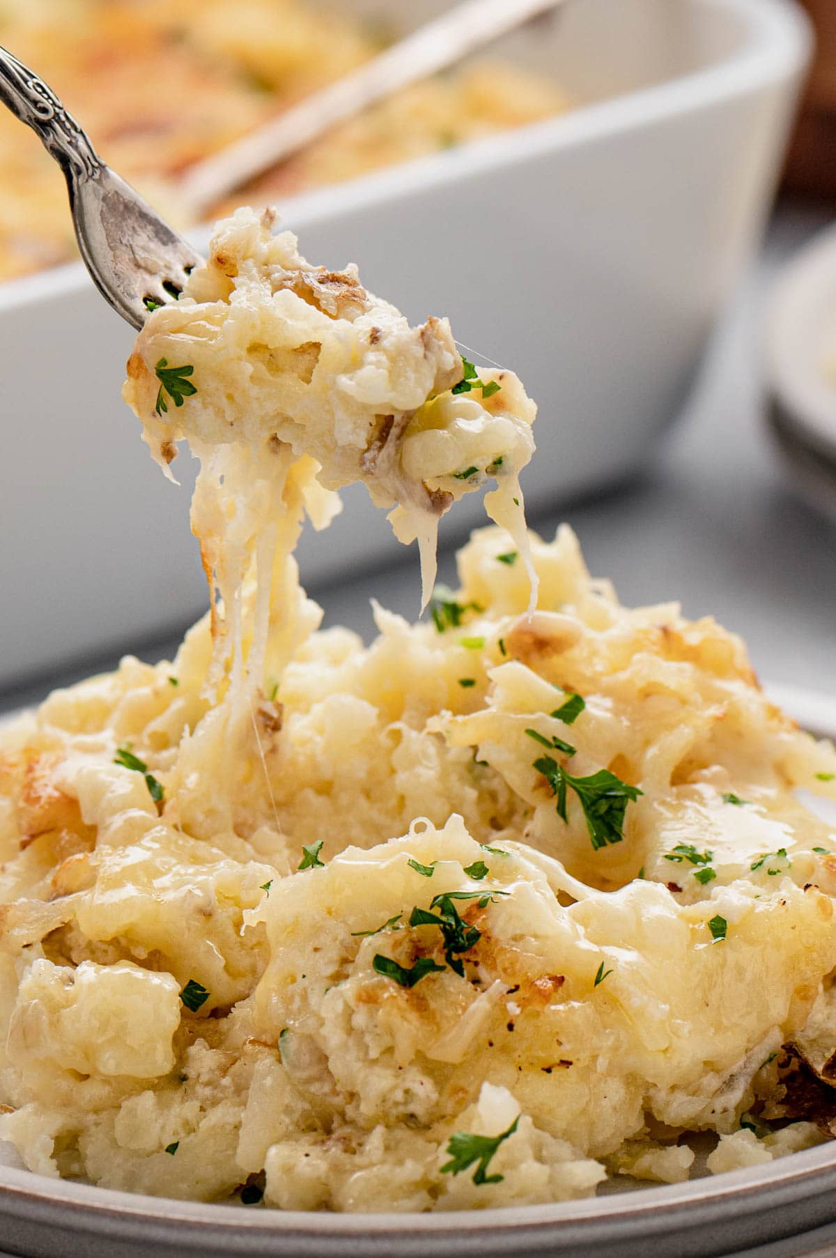 Cheesy Potatoes casserole on a white plate with a fork.