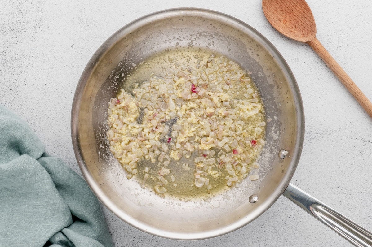 Minced shallots and garlic being sauteed in a skillet.