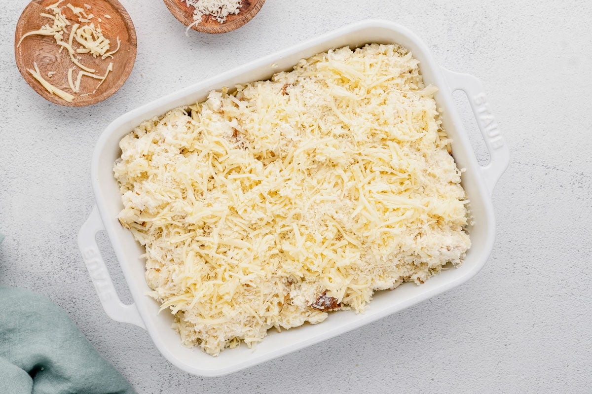 Assembled casserole of shredded potatoes and cheese.
