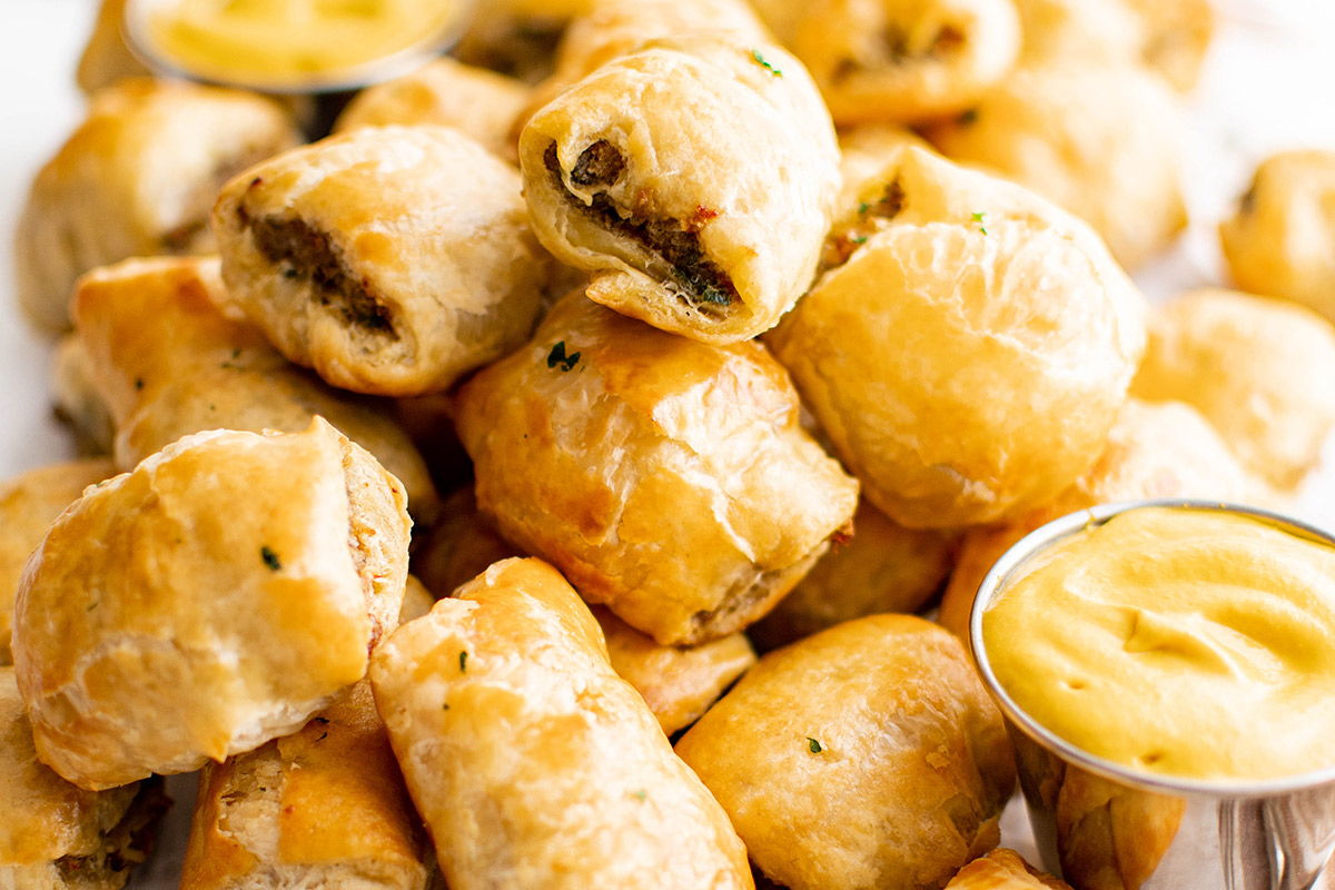 piles of puff pastry with sausage inside, a dish of mustard.