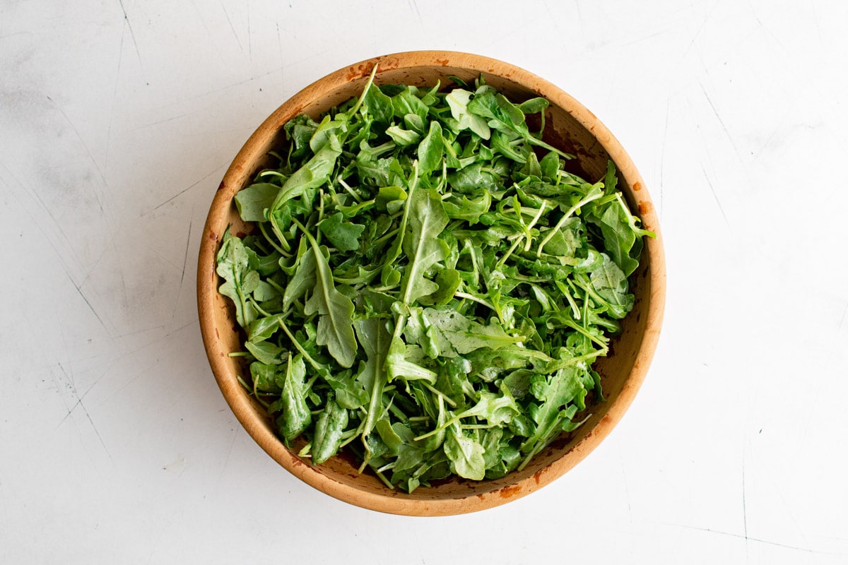 Arugula in a large wooden bowl.