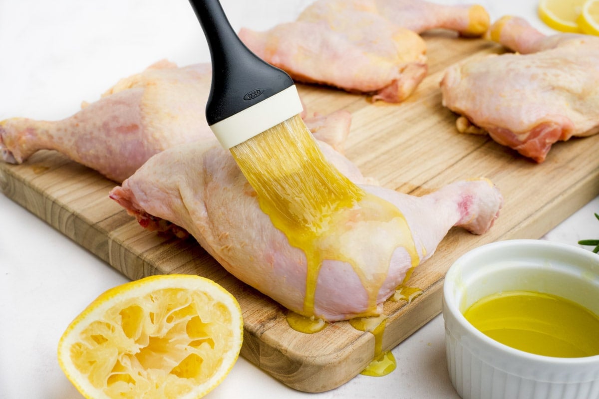 Olive oil being brushed on a chicken leg.