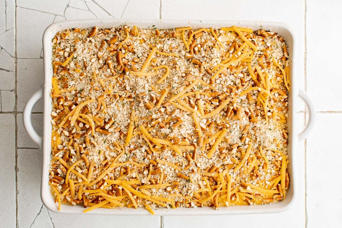 Crushed pretzels sprinkled over mac and cheese in a baking dish.