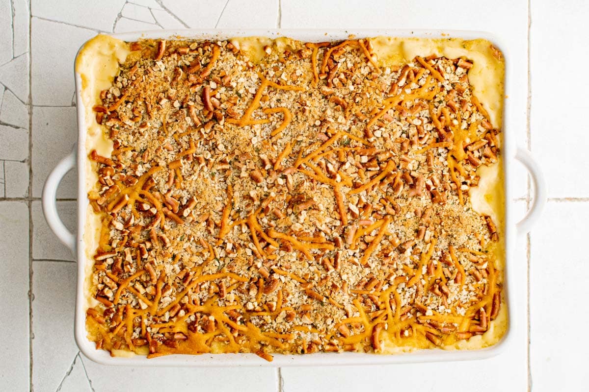 Baked macaroni and cheese with pretzel topping in a white baking dish.