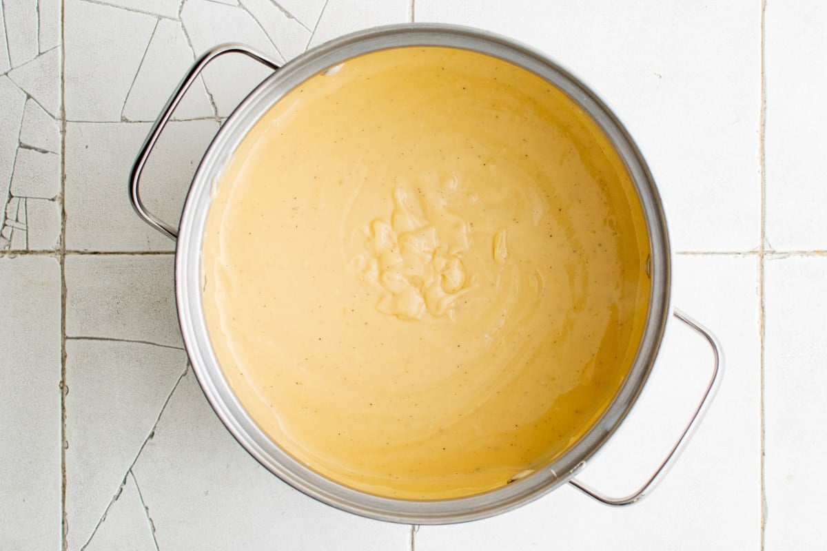 Yellow cheese sauce in a metal pot.